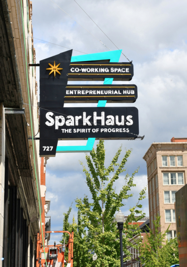 Historic SparkHaus sign hanging with clouds behind